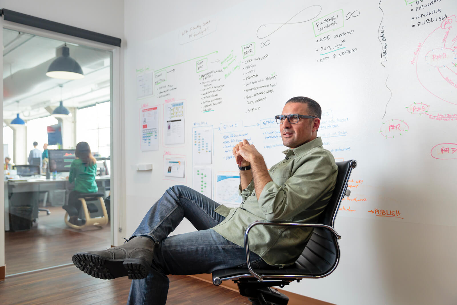 Man sitting in swivel chair near whiteboard in open modern office meeting room